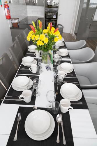 a long table with white plates and yellow flowers on it at KCM Urban Retreats in Cobh