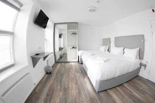a white bedroom with two beds and a television at KCM Urban Retreats in Cobh