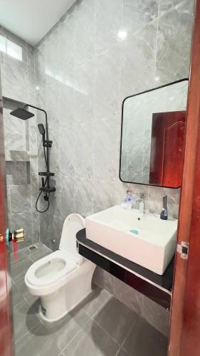 a bathroom with a toilet and a sink and a mirror at BTB Homestay in Phumĭ Kâmpóng Âmpĭl
