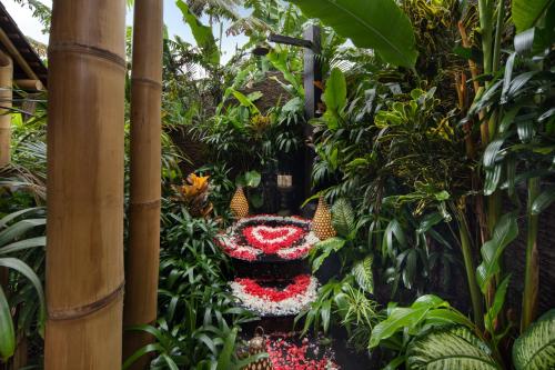 a garden with red and white flowers and plants at Magic Hills Bali - Eco Luxury Adventure in Karangasem