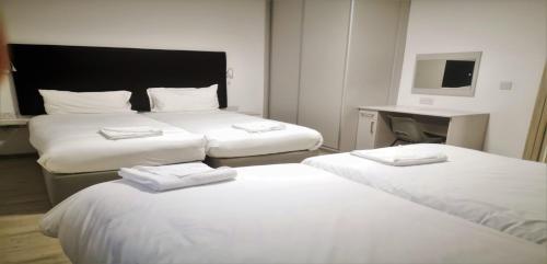 a hotel room with two beds and a desk at KCM Urban Retreats in Cobh