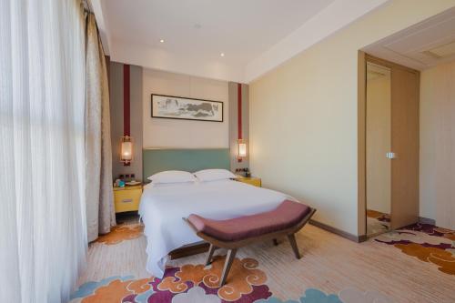 a bedroom with a large white bed and a chair at 济宁银座佳悦精选酒店 in Jining