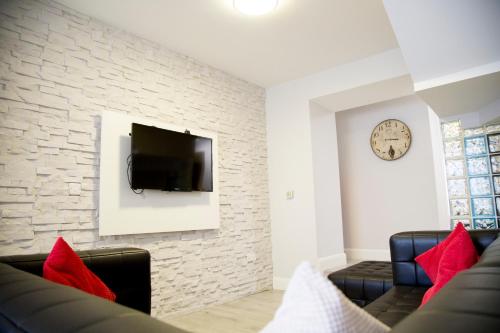 a living room with a couch and a tv on a wall at KCM Urban Retreats in Cobh