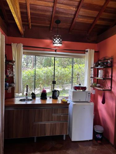 a kitchen with a window and a white refrigerator at Chalés ANECUEM in Monte Verde