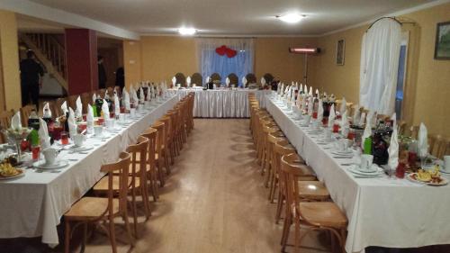 une grande salle de banquet avec de longues tables et chaises dans l'établissement Lauku Mājas Ēmužas, à Dārte