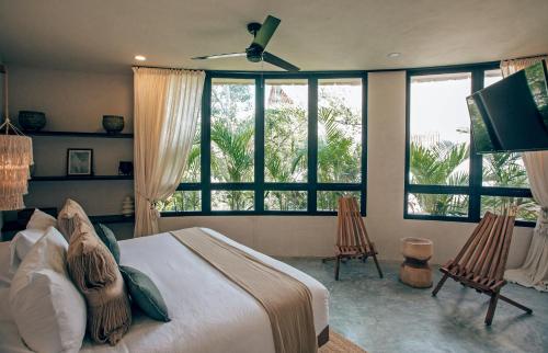 a bedroom with a bed and a tv and windows at Tulum Jungle Luxury Villa -Pvt Pool - Concierge 6A in Tulum