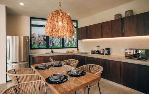 a kitchen with a wooden table with chairs and a chandelier at Tulum Jungle Luxury Villa -Pvt Pool - Concierge 6A in Tulum