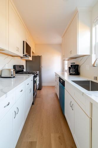 a kitchen with white cabinets and a refrigerator at 2 Palo Alto - Fully Furnished with Parking, Laundry, AC, Private in East Palo Alto