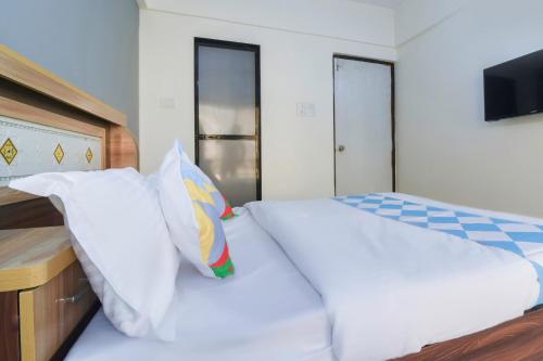 a bed with white sheets and pillows in a bedroom at Hotel O GEMS STAR RESIDENCY BNB Bamandongri Railway Station in Belapurpāda