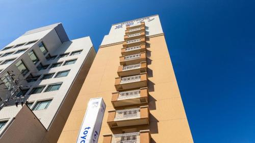 Toyoko Inn Niigata Furumachi في نيغاتا: مبنى طويل بجوار مبنيين طويلين