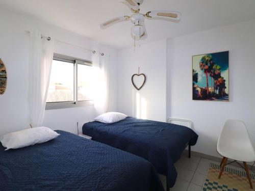 - une chambre avec 2 lits et un panneau cardiaque sur le mur dans l'établissement Spacieux 3 Pièces Climatisé avec Terrasse et Garage - FR-1-307-281, au Grau-du-Roi