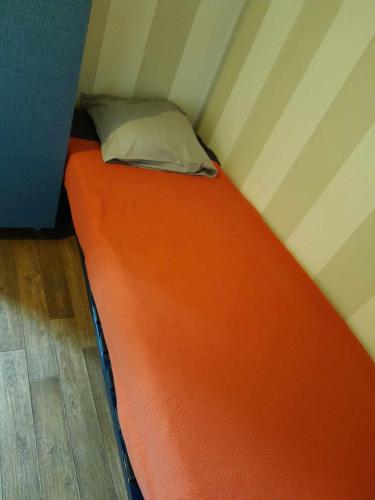 Ce lit se trouve dans une petite chambre dotée d'un matelas orange. dans l'établissement Mobil-home C007 - C008, à Boofzheim