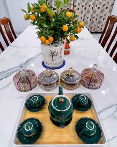 a table with green dishes and a vase with oranges at Nhat Long Homestay in Hue