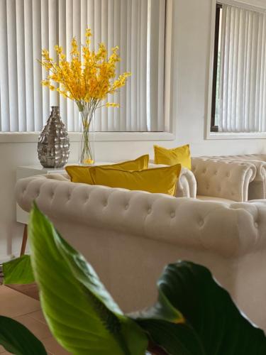 a living room with a white couch and yellow pillows at Campbeltown Private Room in Campbelltown South