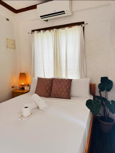 a bedroom with a large white bed with a window at Tahanan Resort in San Juan