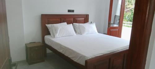 a bed with white sheets and pillows next to a window at The Green Lagoon Villa in Hikkaduwa