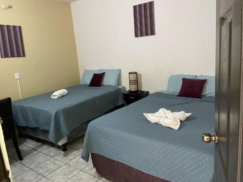 two beds in a hotel room with towels on them at Hotel La Villa in Retalhuleu