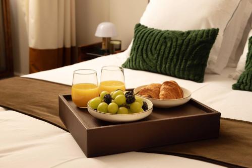 a tray of fruit and croissants and drinks on a bed at Hotel Palais Bourbon in Paris