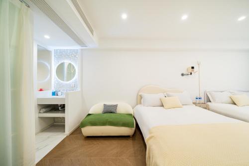a white bedroom with two beds and a green ottoman at Today Aparthotel West Lujiazui Shanghai in Shanghai