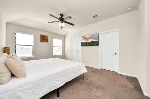a white bedroom with a bed and a ceiling fan at Cozy & Spacious Getaway -4Bedroom With King bed & Backyard in Houston