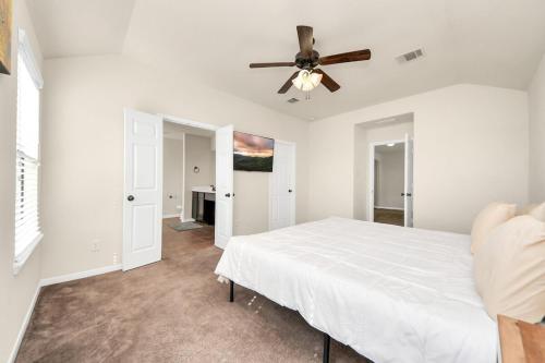 a white bedroom with a bed and a ceiling fan at Cozy & Spacious Getaway -4Bedroom With King bed & Backyard in Houston