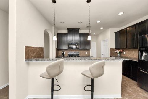 a kitchen with black cabinets and white counter tops at Cozy & Spacious Getaway -4Bedroom With King bed & Backyard in Houston