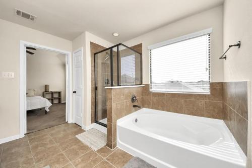 a large bathroom with a tub and a bedroom at Cozy & Spacious Getaway -4Bedroom With King bed & Backyard in Houston