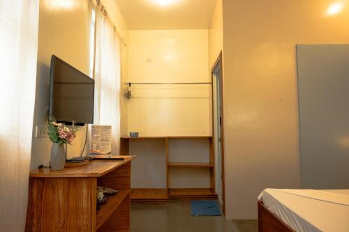 a room with a desk with a television and a bed at AV Suites in Puerto Galera