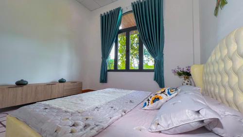 a bedroom with a bed and a window with blue curtains at Nhà Vườn NGô Tất Tố , lộc châu , TP bảo lộc in Ðại Lào