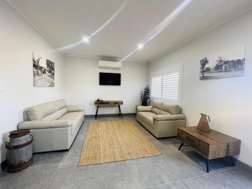 a living room with two couches and a table at Cooper's Cottages in Lightning Ridge