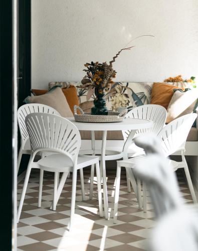 a dining room with a table and white chairs at Monsoon Luxury Apartment in Port Douglas