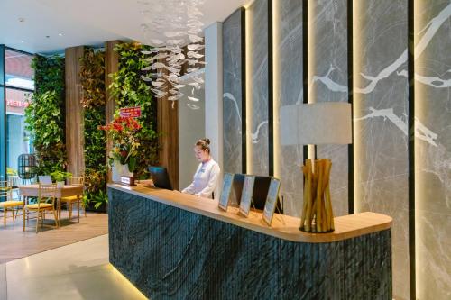 a woman sitting at a reception desk in a lobby at CENTRAL PLAZA HOTEL - Mỹ Tho in My Tho