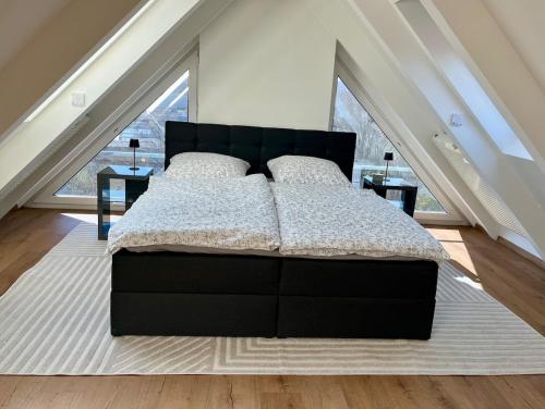 a black bed in a room with a large window at Panoramablick auf Baldeneysee in Essen