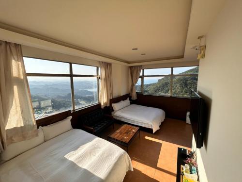 a room with two beds and a table and windows at Old Street Seaview Homestay in Jiufen