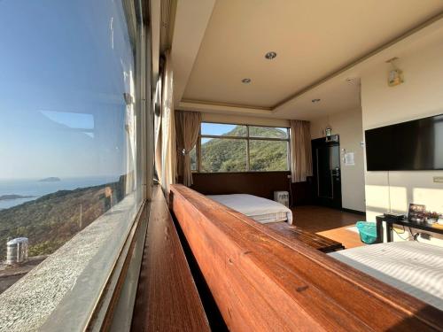 a bedroom with two beds and a large window at Old Street Seaview Homestay in Jiufen