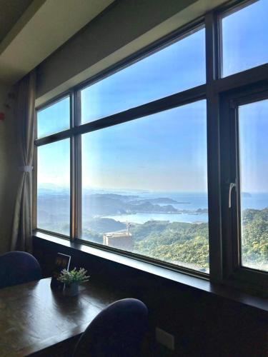 a room with a large window with a table and chairs at Old Street Seaview Homestay in Jiufen