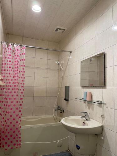 a bathroom with a sink and a shower curtain at Old Street Seaview Homestay in Jiufen