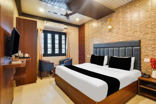 a bedroom with a bed and a desk and a television at Hotel O Canal Road in Dehradun
