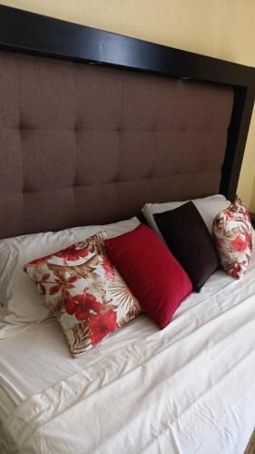 a bed with three pillows on top of it at Departamento Tapatío in Guadalajara