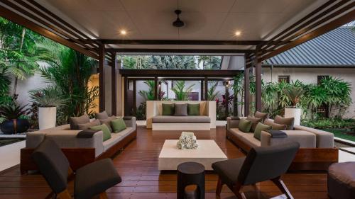 a living room with couches and chairs and plants at Niramaya Villas and Spa in Port Douglas