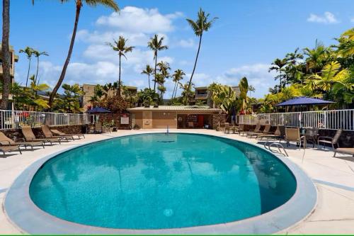a large swimming pool with chairs and palm trees at Cozy 1 Bdrm Condo at Ali'i Villas in Kailua-Kona