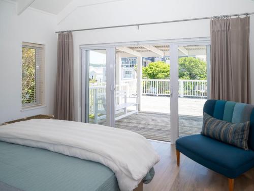 a bedroom with a bed and a chair and a balcony at Thesen Island Villas in Knysna