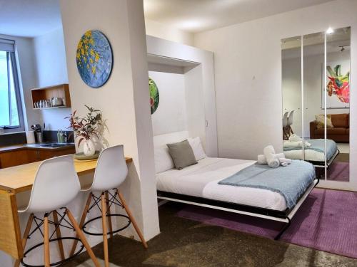 a small room with a bed and a table and chairs at Eco Gallery Apartment in Fremantle