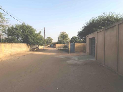 an empty road next to a wall with a gate at Small air-conditioned apartment with private pool in Warang