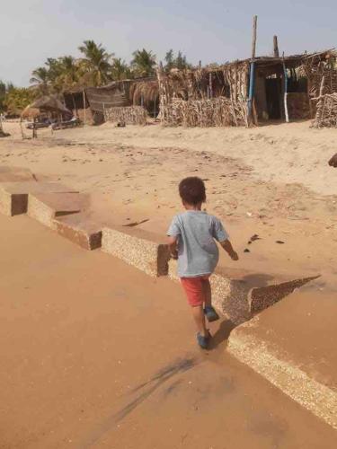 a young boy walking on the beach at Small air-conditioned apartment with private pool in Warang