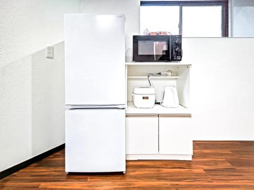 a white refrigerator in a kitchen with a microwave at YayoiHotel in Tokyo