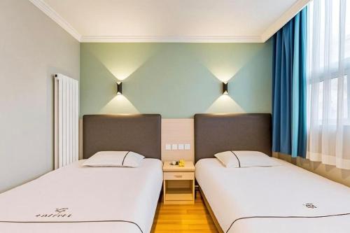 two beds in a room with blue walls at Qiqiaowu Hotel Beijing Daxing Airport Line Caoqiao Subway Station Branch in Beijing