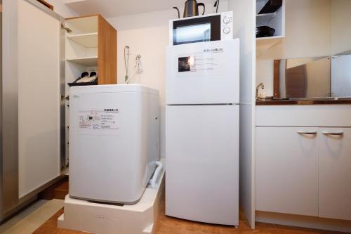 a white refrigerator in a kitchen with a microwave at Zenith Garden TOGOSHI in Tokyo