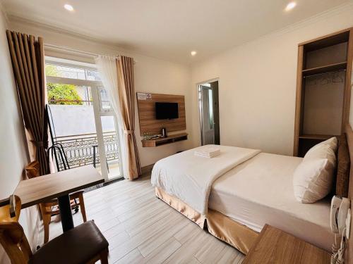 a bedroom with a bed and a window and a television at Bee Luxury Dalat Hotel in Xuan An