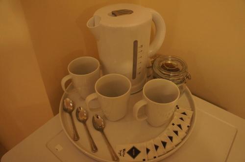 un plateau avec des tasses et des cuillères sur une table dans l'établissement Sapphire Hotel London, à Londres